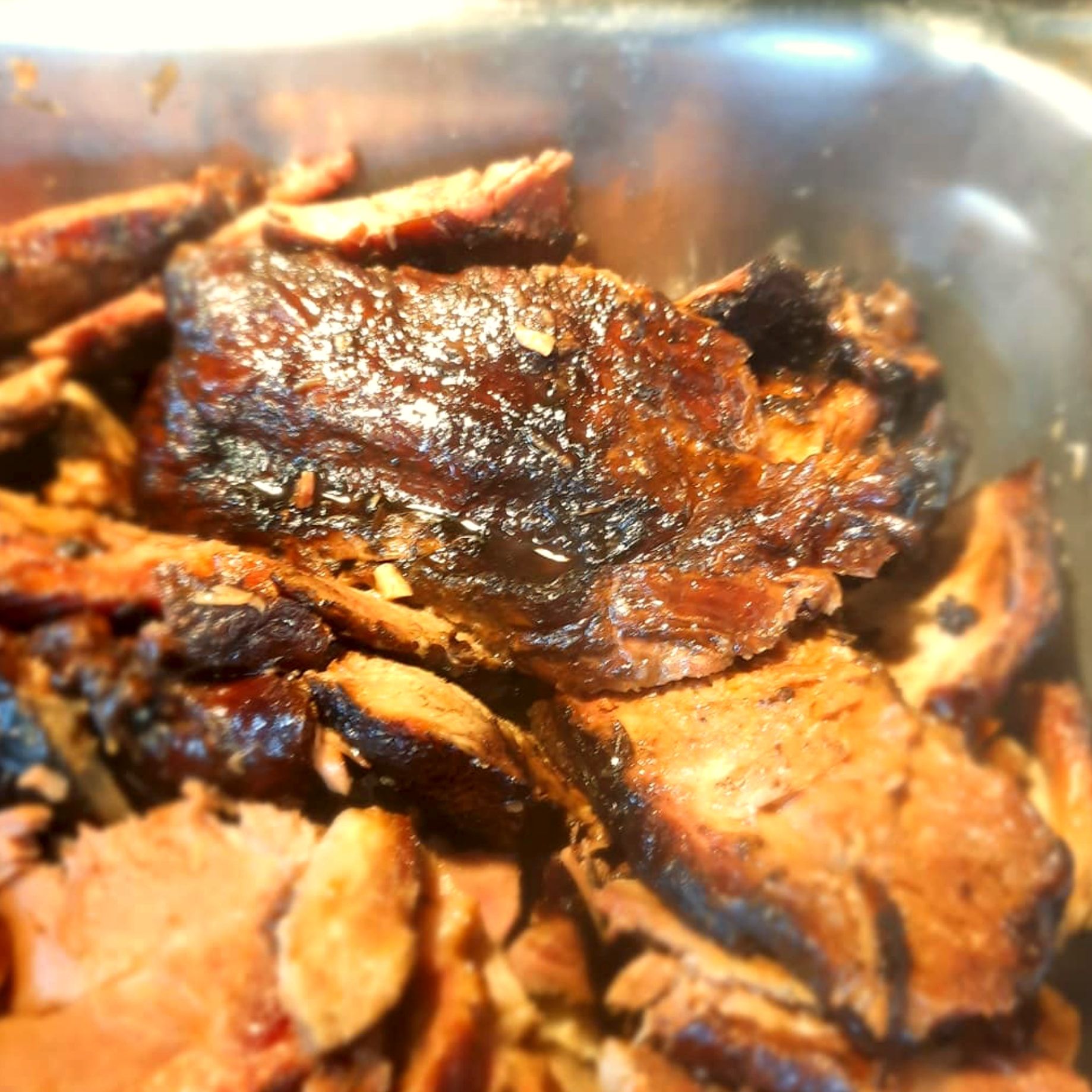 Barbecue with dark, crusty edges in a steel pan at The Pit